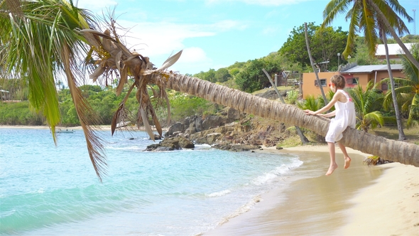 Adorable Little Girl Sitting on Palm Tree During Summer Vacation on White Beach