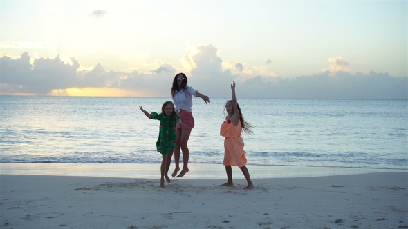 Adorable Little Girls and Young Mother on White Beach