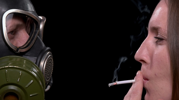 Young Man in Gas Mask To Protect Cigarette Smoking Friend From Harm