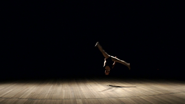 Little Girl Gymnast Doing a Somersault on a Stage.