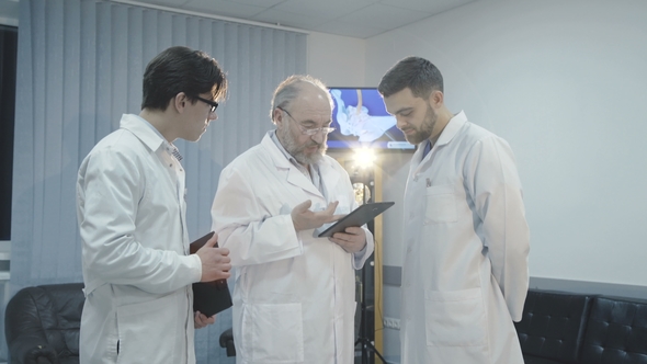 Three Male Doctors Discuss a Patient's Diagnosis in Hospital.