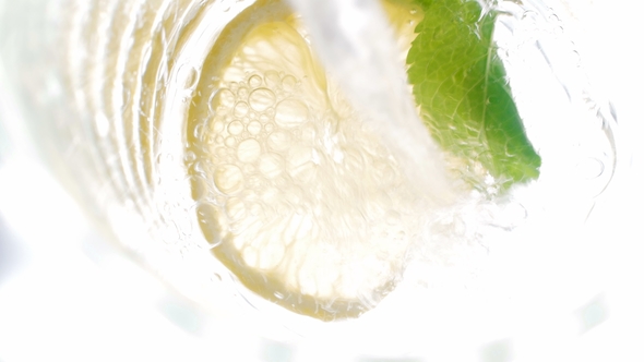 Footage of Pouring Cold Water in Jar with Cut Lemons, Mint and Ice Cubes