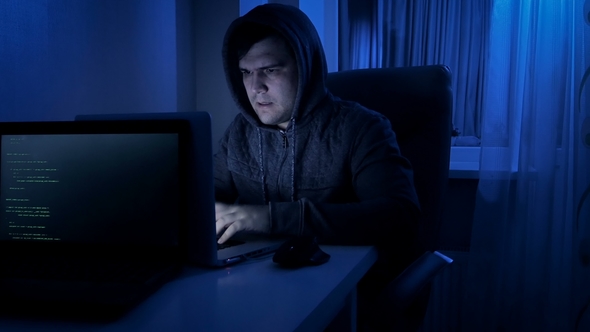 Footage of Stressed Man in Hood Working on Laptop at Home at Night