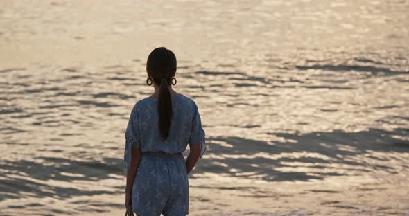 Woman stand on the beach and enjoy the view of the sea at sunset time