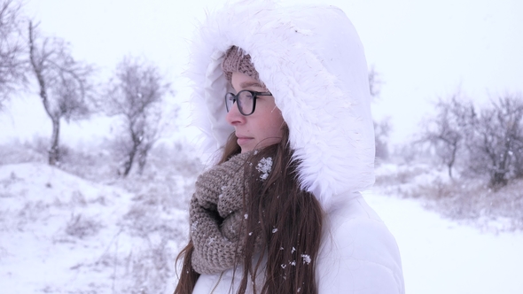 Portrait of Lovely Female Spectacled Standing under Snowfall in Winter