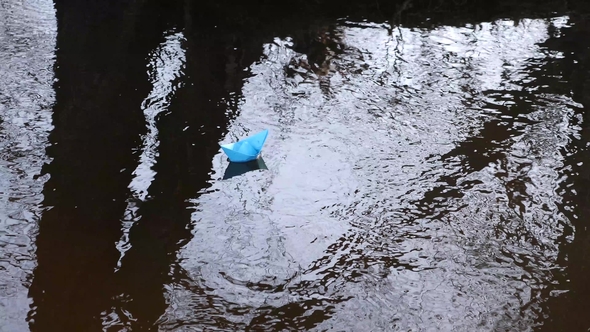 Small Blue Paper Boat Flowing with a Stream of Transparent River