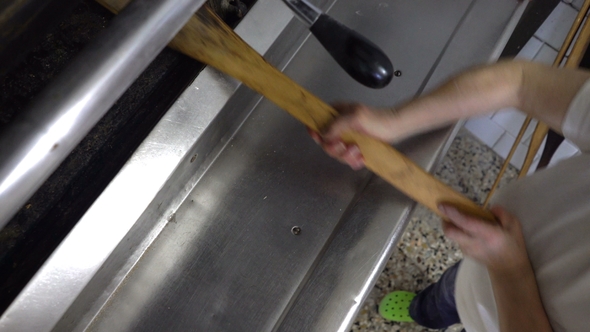 Traditional Italian Bakery. The Woman Baker Puts the Bread in the Oven for Baking By Using