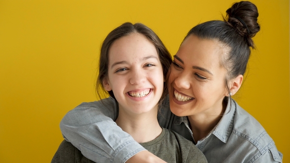 Happy Laughing Sisters on Yellow Background