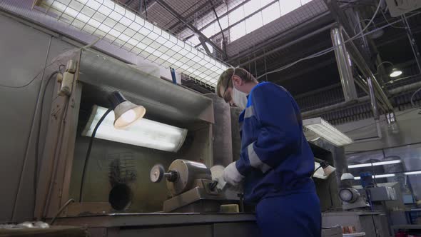 Worker at the Plant Burnishing the Finished Silver Spoon with a Machinetool