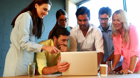 Businesspeople having a discussion while using laptop