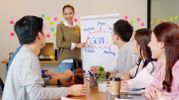 Cheerful young asian woman standing smiling and presentation on whiteboard