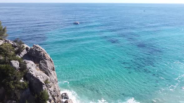 Drone flight with light waves over the bay of Cala Fuili (Sardinia) out to sea, sunny weather