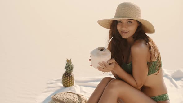 Woman Drinking Coconut Juice While Relaxing on the Beach