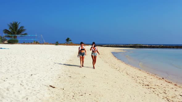 Women happy together on exotic shore beach vacation by clear lagoon with white sandy background of K