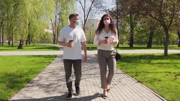 Sequence of Man and Woman in Face Masks Walking through Park