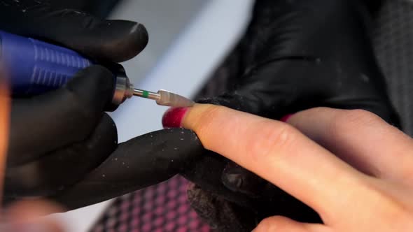 Skilled Beautician in Black Gloves Handles Red Manicure