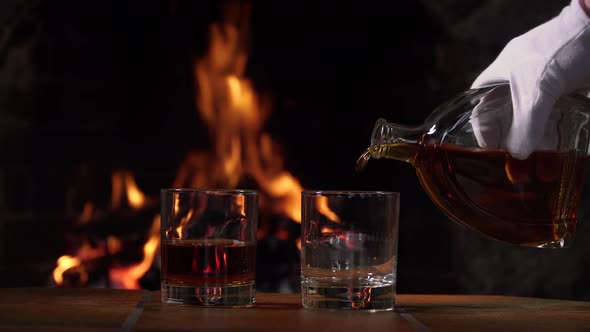 Cognac is Poured From a Bottle on the Background of Fire in the Fireplace