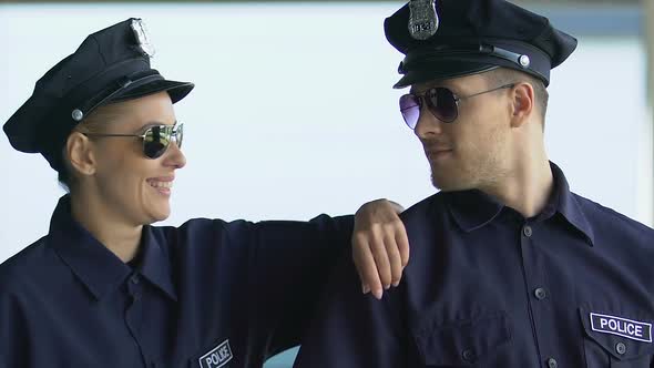 Male and Female Police Officers in Sunglasses Smiling Into Camera, City Patrol