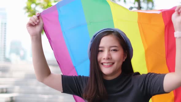 Happy loving homosexual lesbian LGBT couple with rainbow flag at city streets