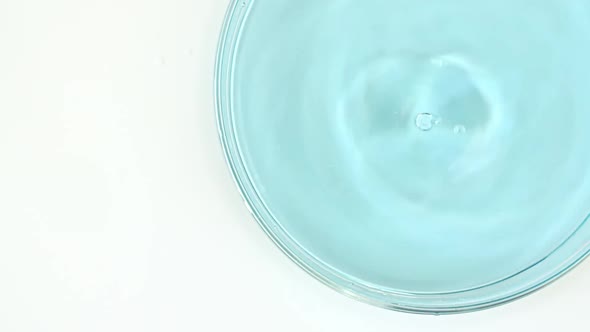 Transparent Blue Cosmetic Liquid Dripping in a Glass Bowl of Petri
