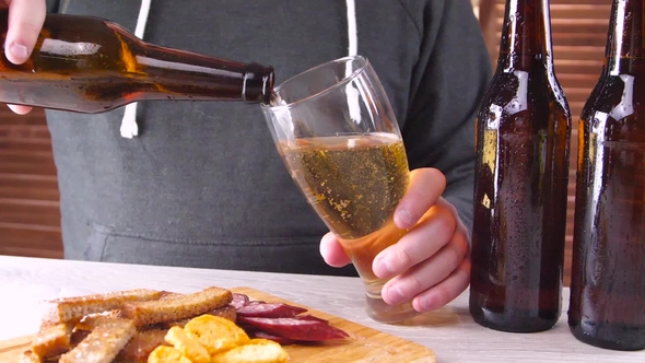 Man Pours Beer into Glass from Bottle