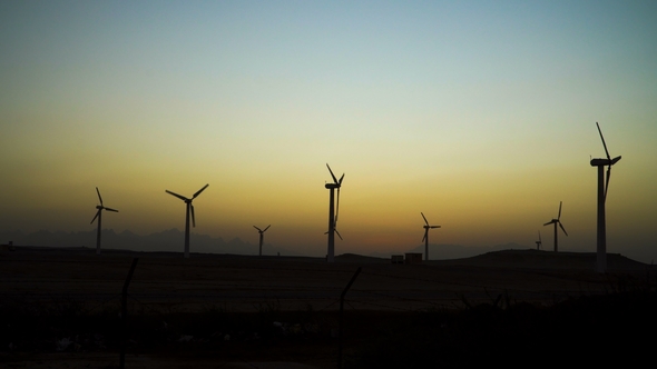 Beautiful Windmill Turbines Harnessing Clean, Green, Wind Energy Silhouetted in the Sunset Sky with