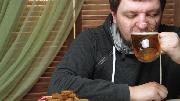 Man Drinks Beer and Eats Beer Snacks