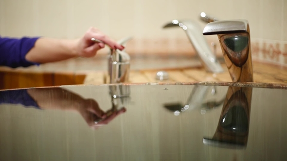 Hand Opens the Tap and the Water Begins to Flow