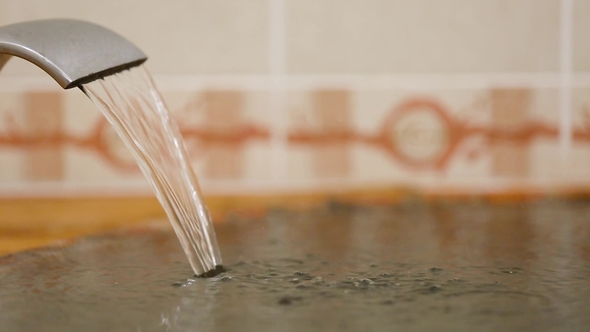 Water Pouring from Bathroom Faucet and Water Bubbles