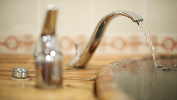 Water Stream Flows from the Water Tap into the Tub