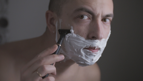 Man Shaving His Face with a Razor with the Help of a Special Foam