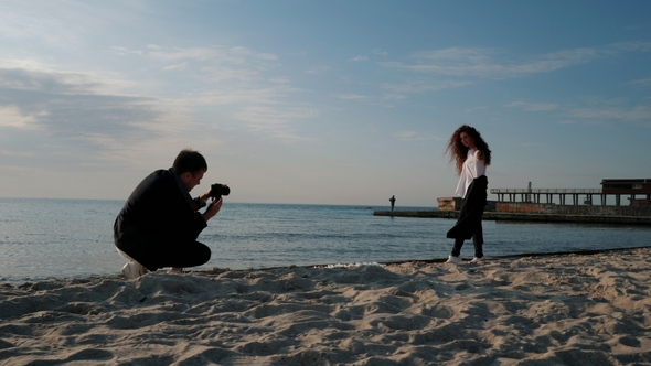 Man Takes Pictures of His Beloved on the Seashore in Spring. Photoshoot of Beautiful People on the