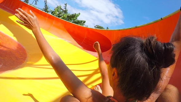 Young Mixed Race Couple Having Fun Riding down in a Water Slide