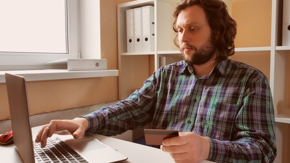 Handsome Male Sitting at the Desk Shopping Online