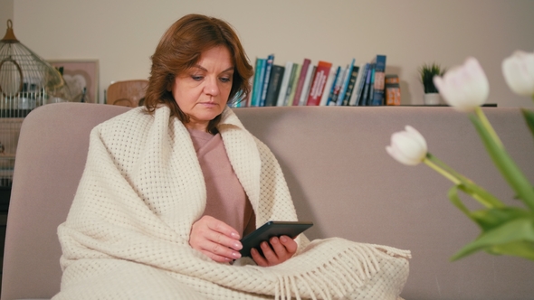 Adult Lady Is Reading eBook Using Tablet in a Cozy Room with Traditional Books