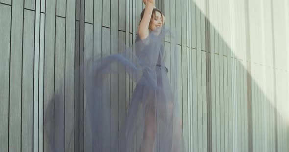 Young lady standing against the wall with a light gray flying dress.