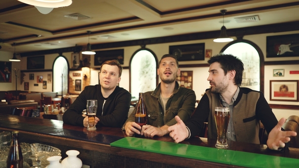 Cheerful Young Men Watching Football Match, Cheering and Drinking