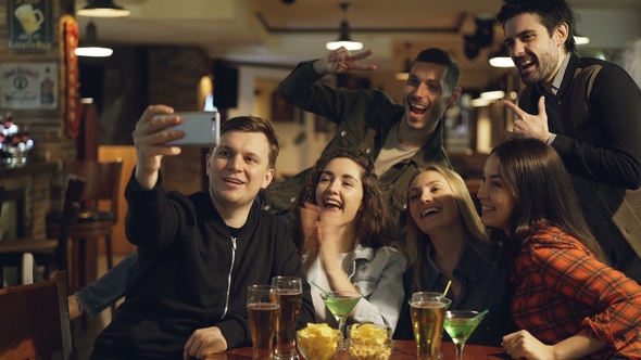 Happy Friends Are Taking Selfie While Sitting at Table with Drinks and Snacks in Cafe