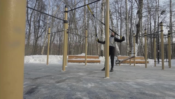 Young Man Training with Fitness Straps on Winter Sport Ground Outdoor