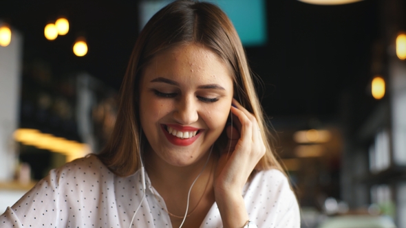 Young Beautiful Businesswoman Listening Music in Headphones at Cafe