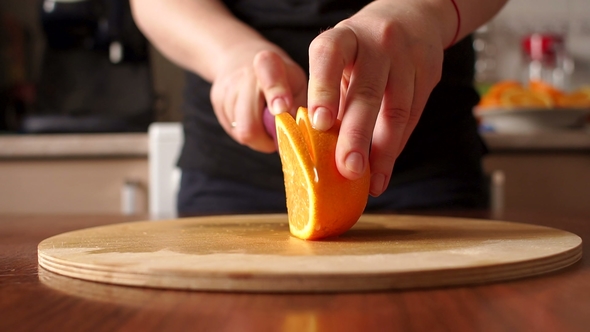 Woman's Hands Cutting Fresh Orange on Kitchen.