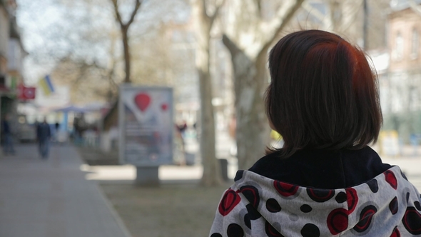 Sportive Woman in a Casual Hoodie Strolls Along a Sunny Street 