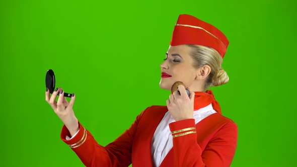 Stewardess Looks in the Mirror and Paints Her Face with a Tassel. Green Screen