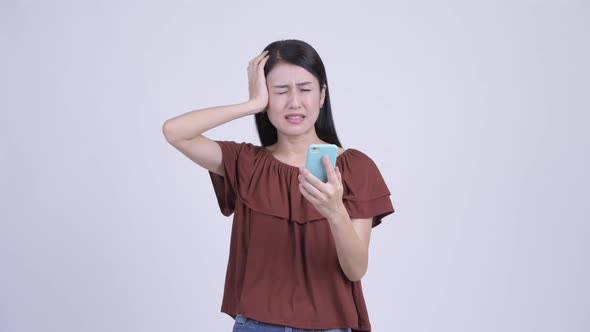 Stressed Asian Woman Using Phone and Getting Bad News