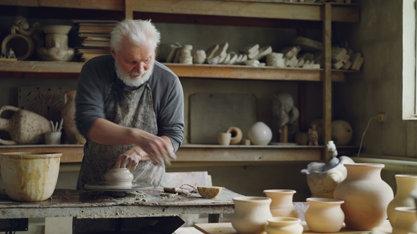 Experienced Ceramist Is Creating Utensils From Clay on Throwign Wheel in Workshop