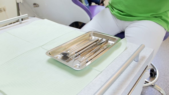 Dentist in Protective Gloves Takes Sterile Instrument From Metal Tray