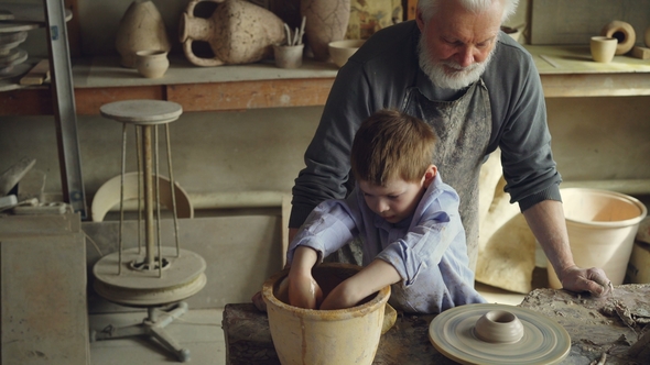 Cute Boy Is Wetting Hands in Bowl and Watering Clay Figure on Throwing Wheel 
