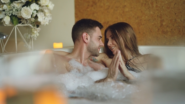Newly Married Couple Relaxing in Jacuzzi Kissing, Touching Hands, Talking and Laughing
