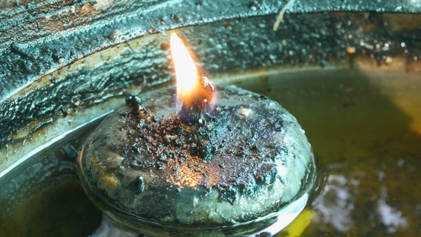 Round Iron Candle with Eternal Fire in Special House. Buddhist Offering To the Gods in the Form of