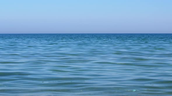 Quiet blue sea overlooking the clear sky from the beach. Summer bright sunny day.